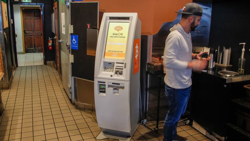 A man prepares his coffee next to a bitcoin ATM at a San Diego coffee shop.