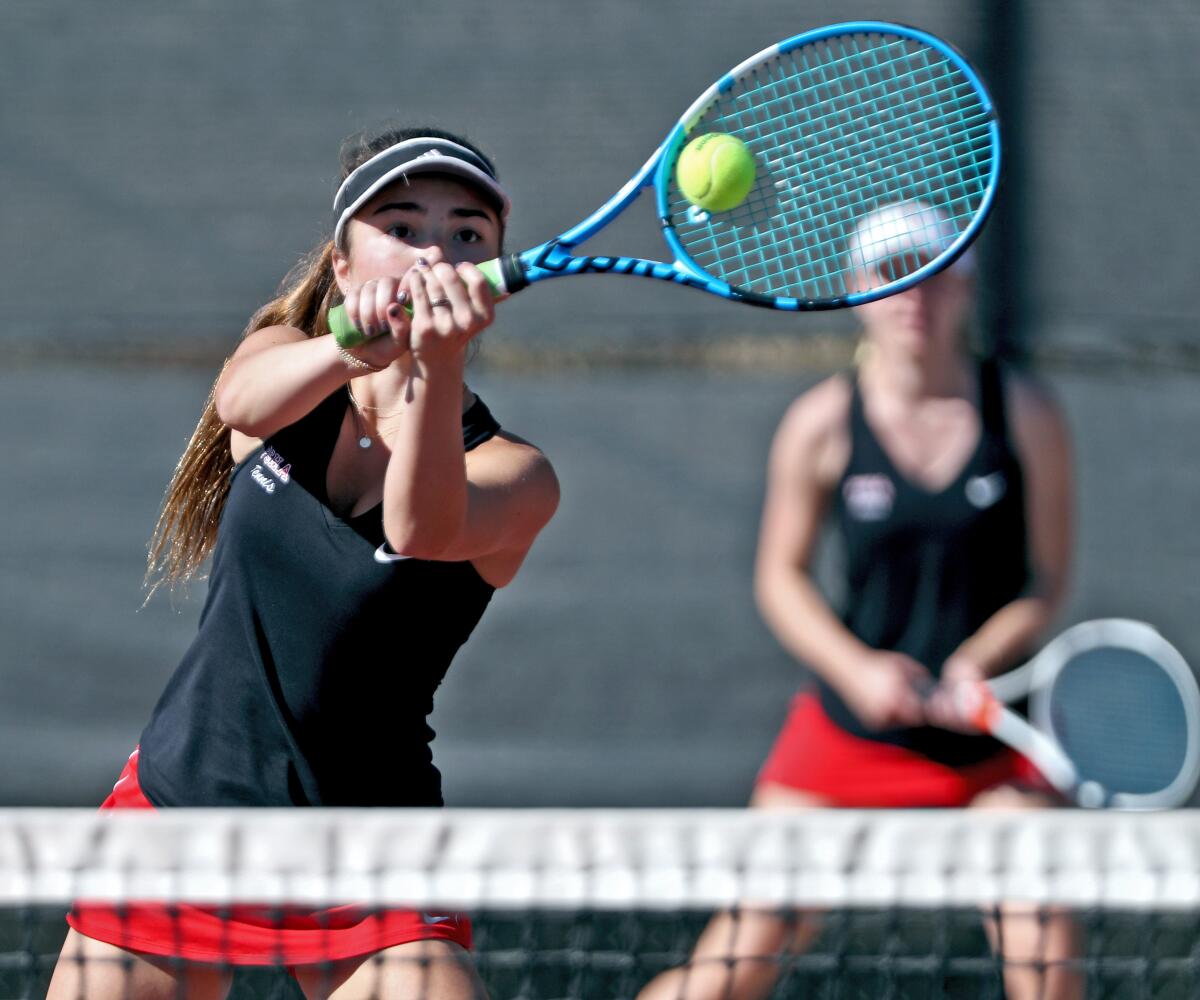 Flintridge Sacred Heart Academy tennis player Hayes Sullivan returns a shot as teammate Claire McDonald looks on during a Sunshine League match against visiting Alemany at Scholl Canyon Tennis Center on Tuesday.