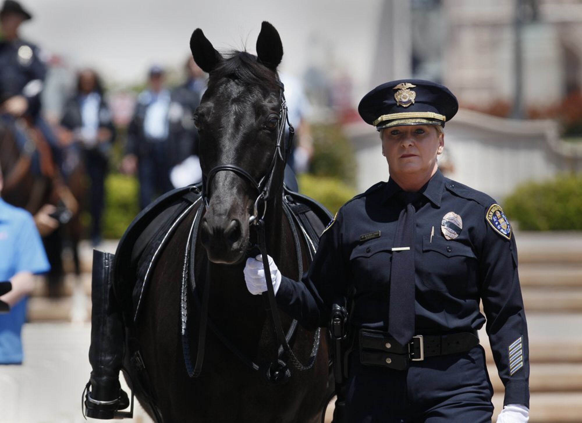 Then-Police Detective Maura Mekenas-Parga leads a police horse at a ceremony for a fallen officer.