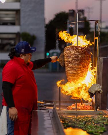 A grill master tends to the al pastor spit at Ave 26 Tacos.