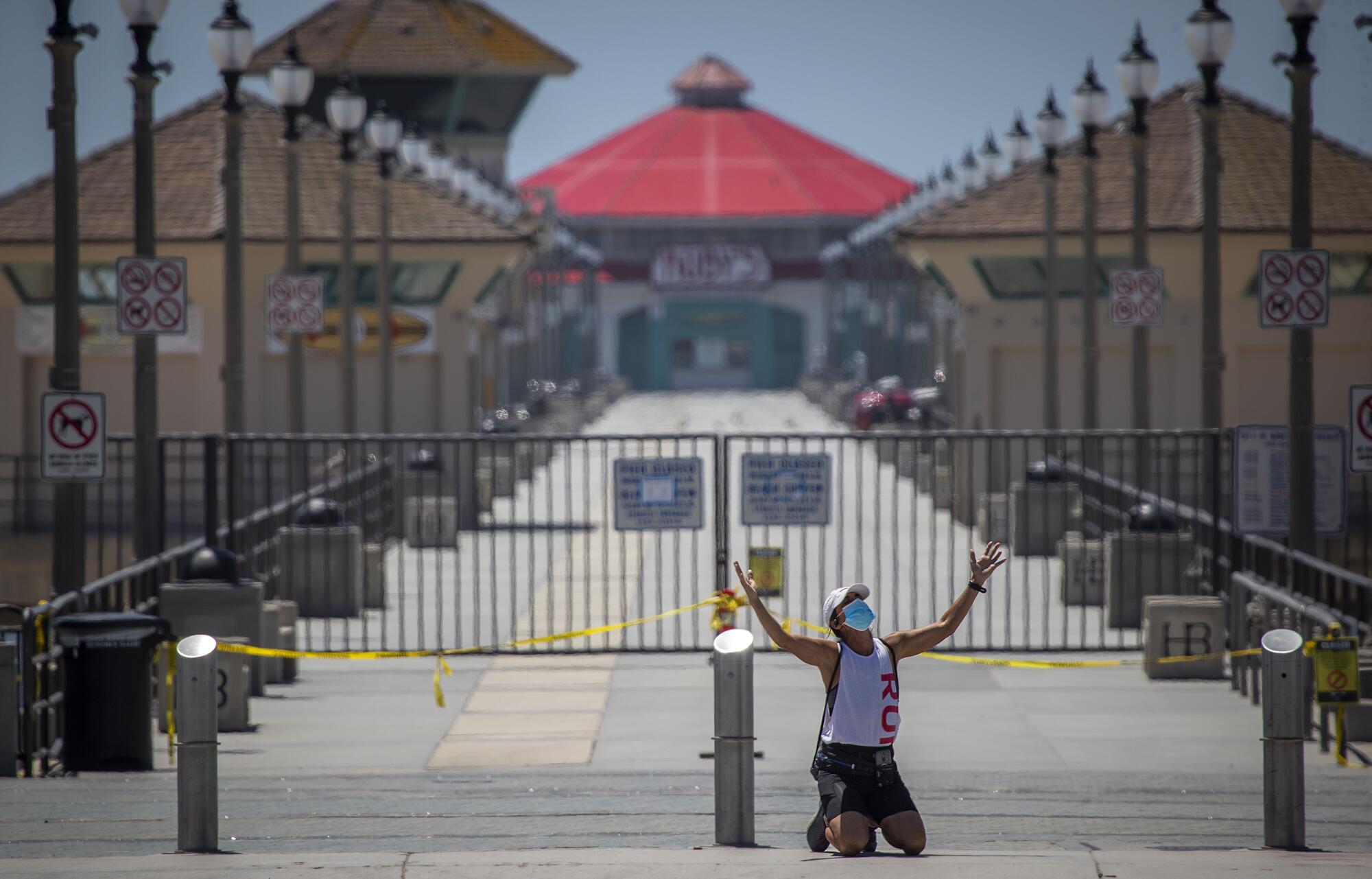 Denise Martinez of Costa Mesa prays in front of the closed Huntington Beach Pier.