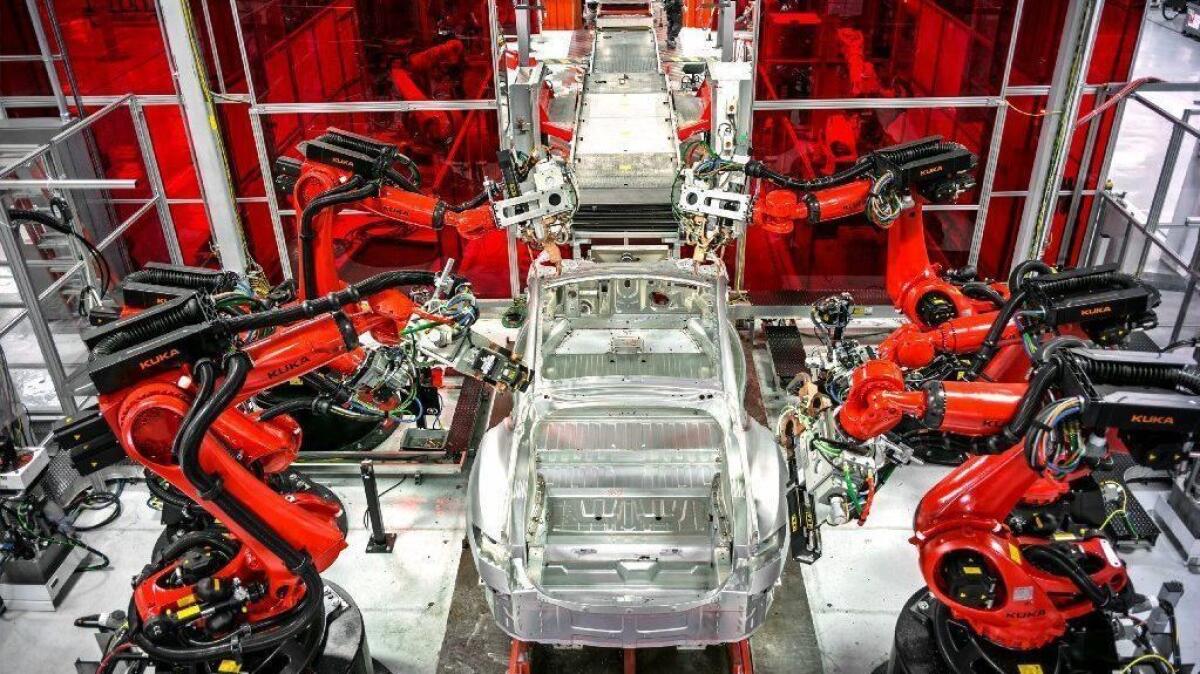 Robots dominate an assembly line at the Tesla car factory in Fremont, Calif.