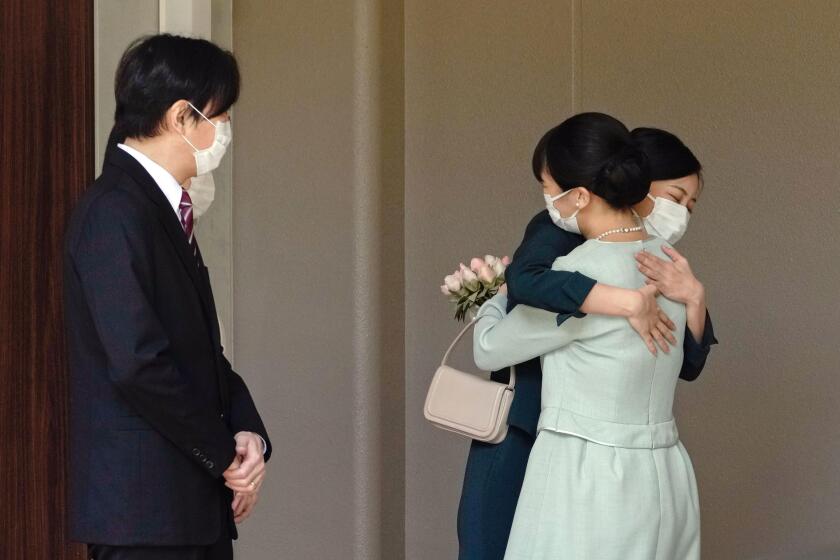 Japan's Princess Mako, right, hugs her sister Princess Kako, watched by her parents Crown Prince Akishino and Crown Princess Kiko, before leaving her home in Akasaka Estate in Tokyo Tuesday, Oct. 26, 2021. Mako and her commoner boyfriend Kei Komuro tied the knot Tuesday without wedding celebration in a marriage that has split the public opinion over her would-be mother-in-law’s financial controversy. (Koki Sengoku/Kyodo News via AP)