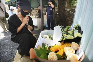 A Chinese woman offers a prayer in front of a Japanese school for a Japanese boy who was stabbed.