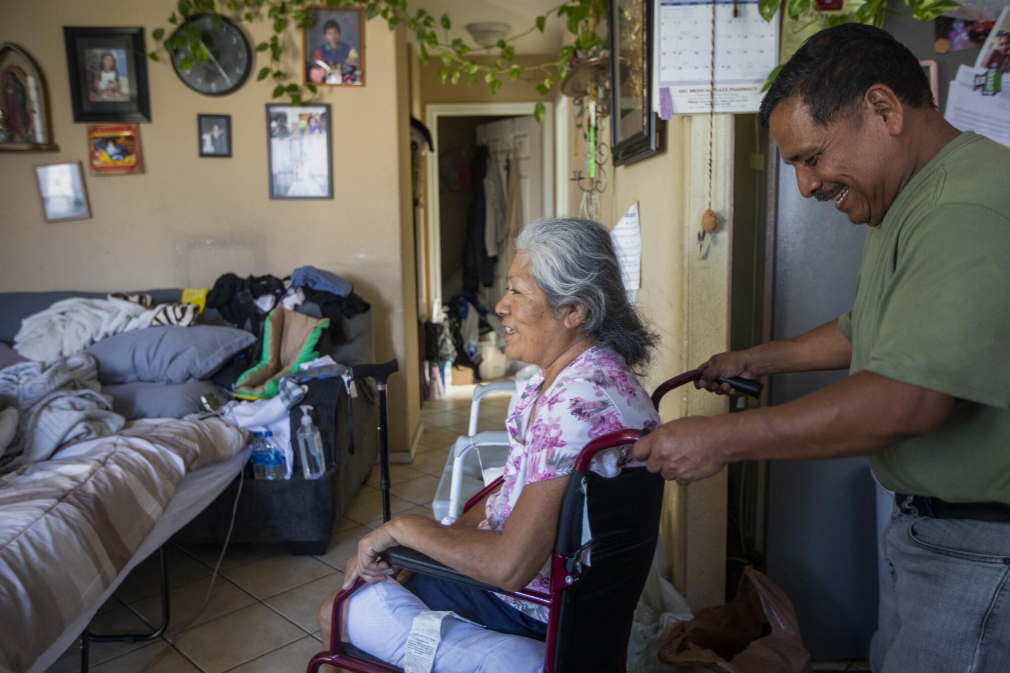 Jose Morales helps his wife, Reyna Chautla, to the dinner table at their home.