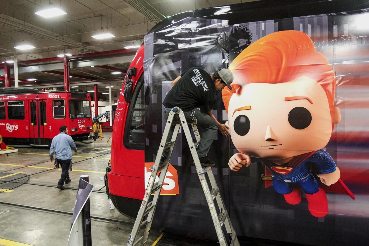 Anthony Soltero works on a section of transit vinyl as he and a crew put on an advertising wrap for TBS television host Conan O'Brien's talk show on a trolley car.
