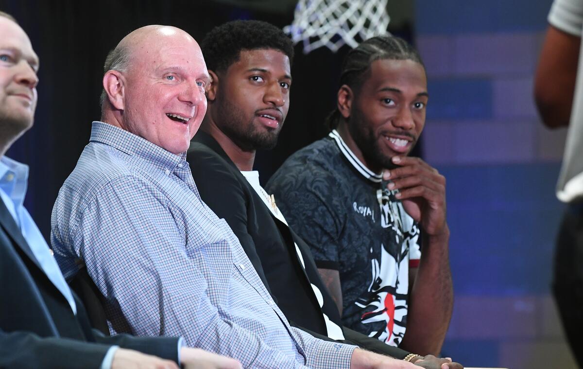 Clippers owner Steve Balmer with new players Paul George, center, and Kawhi Leonard at Green Meadows Recreation Center in Los Angeles in July.