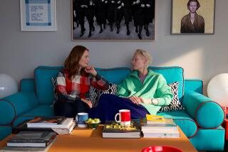 Two women sit on a couch, chatting.