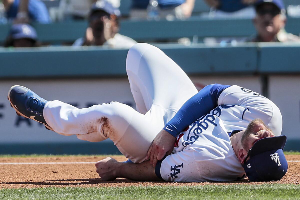 Dodgers first baseman Max Muncy writhes in pain after colliding with Milwaukee Brewers second baseman Jace Peterson.