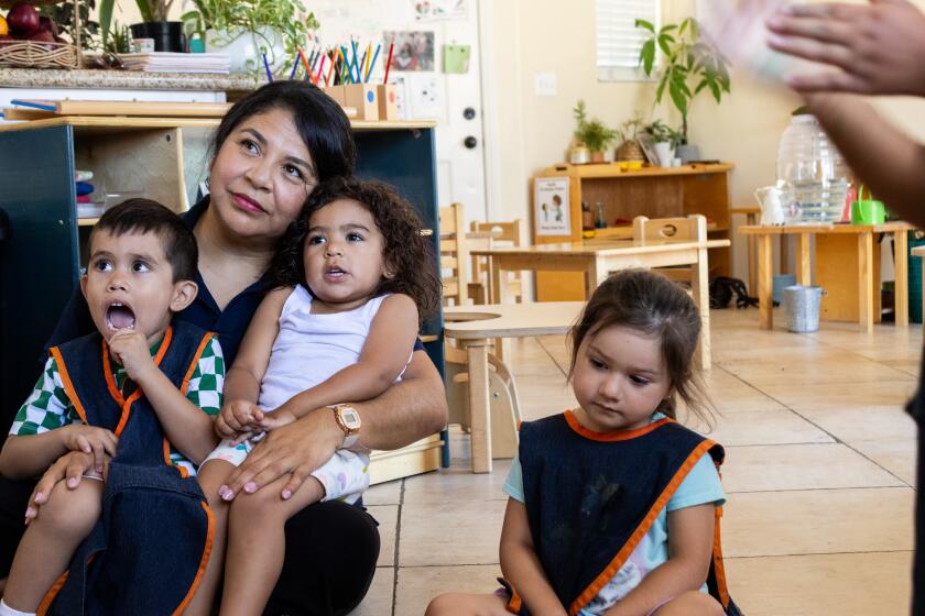 Chula Vista, CA - July 20: During "Circle Time," Karla Diaz holds Rafael Ortiz, 3, left, and Claire Fisher, 2, center, on her lap while Ella Valdovinos, 2, right, sits next to them at Diaz's home in Chula Vista on Thursday, July 20.