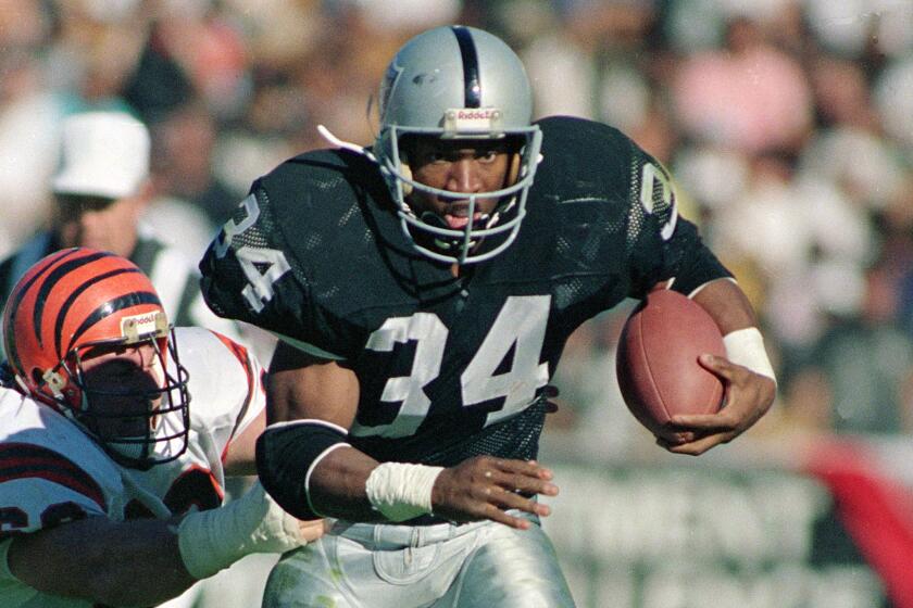 Raiders running back Bo Jackson is seen carrying the ball and running past a Bengals player
