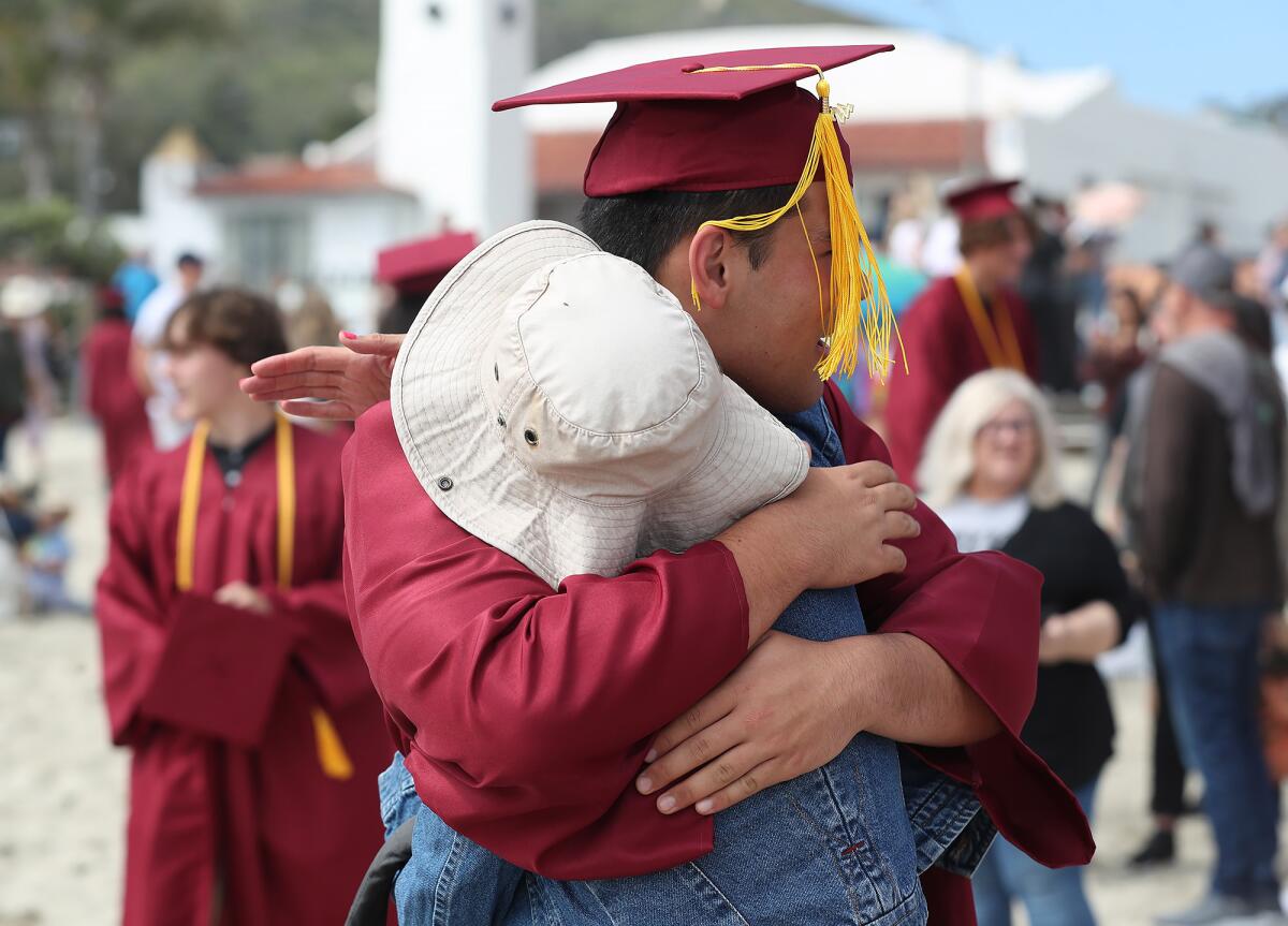Graduate Joshua Burdick hugs his mom following the traditional "grad walk" at Main Beach Park on Wednesday in Laguna Beach.