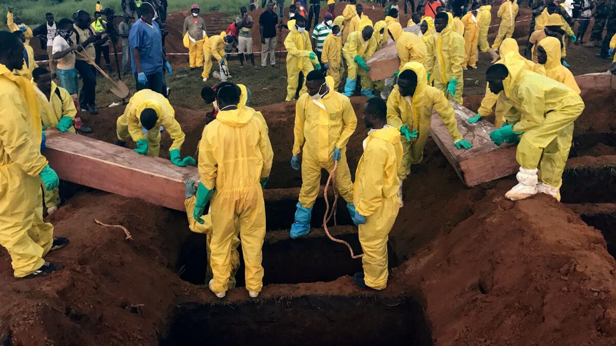In this Aug. 17 photo, volunteers handle a coffin during a mass funeral for victims of heavy flooding and mudslides in Freetown, Sierra Leone.
