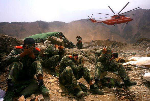 Soldiers take cover as a helicopter delivers supplies to drain the Tangjiashan mountain "quake lake" in Beichuan County, China. China plans to evacuate 100,000 people threatened by the swelling lake formed by the recent earthquake. China's Water Ministry has said 69 dams were in danger of bursting.