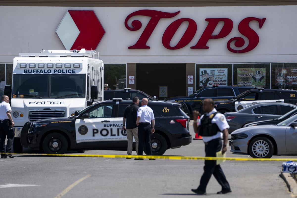 Police tape and vehicles outside a Tops market.