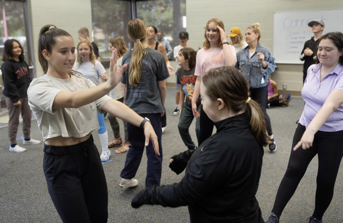 Emma Chaix, left, of the Newport Harbor Dance Team helps lead a dance class for kids.
