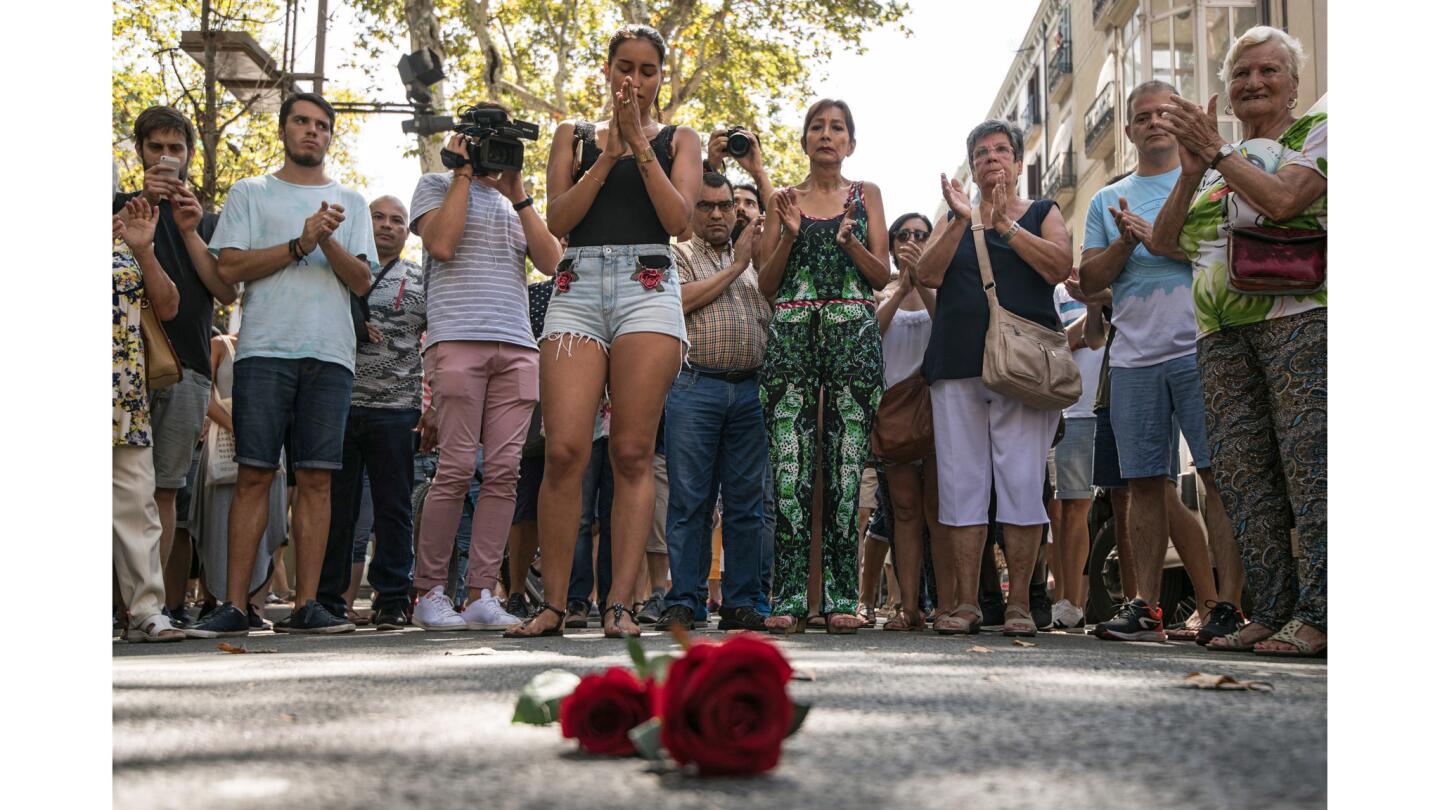 People gather around roses laid on the ground on Las Ramblas after one minute's silence for the victims of Thursday's terrorist attack in Barcelona, Spain.