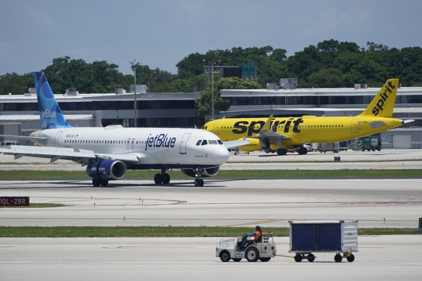 FILE - A JetBlue Airways Airbus A320, left, passes a Spirit Airlines Airbus A320 as it taxis on the runway, July 7, 2022, at Fort Lauderdale-Hollywood International Airport in Fort Lauderdale, Fla. JetBlue Airways said Thursday, June 1, 2023, that it has agreed to sell Spirit Airlines’ holdings at New York’s LaGuardia Airport to Frontier Airlines if it succeeds in buying Spirit. (AP Photo/Wilfredo Lee, File)