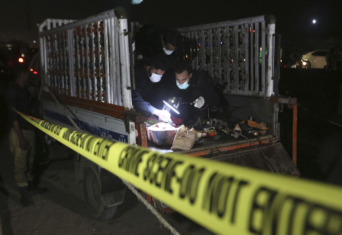 Pakistani investigators examine a truck at the site of an explosion, in Karachi, Pakistan, Saturday, Aug. 14, 2021. Attackers targeted a truck in the Pakistani port city of Karachi, killing multiple people and wounding others. An initial investigation suggests the attackers followed the truck and then threw hand grenades or some sort of improvised explosive devices at one side of the truck, police said. (AP Photo/Fareed Khan)