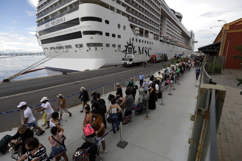 Passengers disembark from the cruise ship 'MSC Preziosa'', in the Port Area of Rio de Janeiro, Brazil, Sunday, Jan. 2, 2022, after Brazil's Sanitary Agency has confirmed more cases of COVID-19 on board. Rio's Health Secretariat said that those living in the city or nearby regions will be quarantined in their homes. Those who live outside the state will be isolated in hotels. (AP Photo/Bruna Prado)