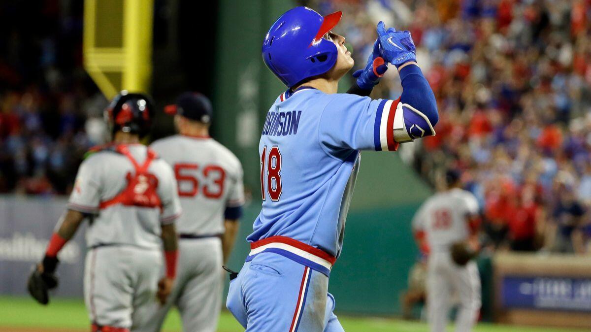 Texas Rangers' Drew Robinson (18) points skyward as he approaches the plate after hitting a two-run home run off Angels relief pitcher Blake Parker (53) during the sixth inning Saturday.