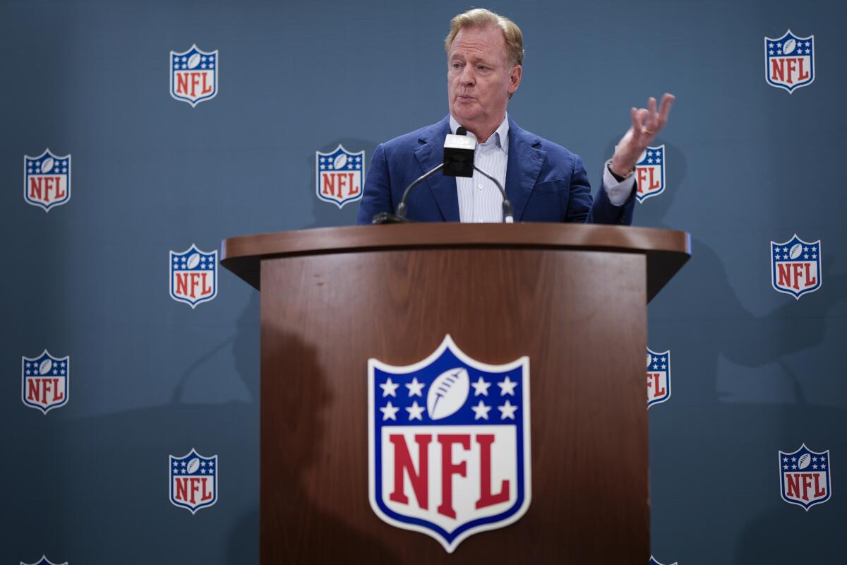NFL commissioner Roger Goodell stands behind a lectern and responds to questions during a news conference 