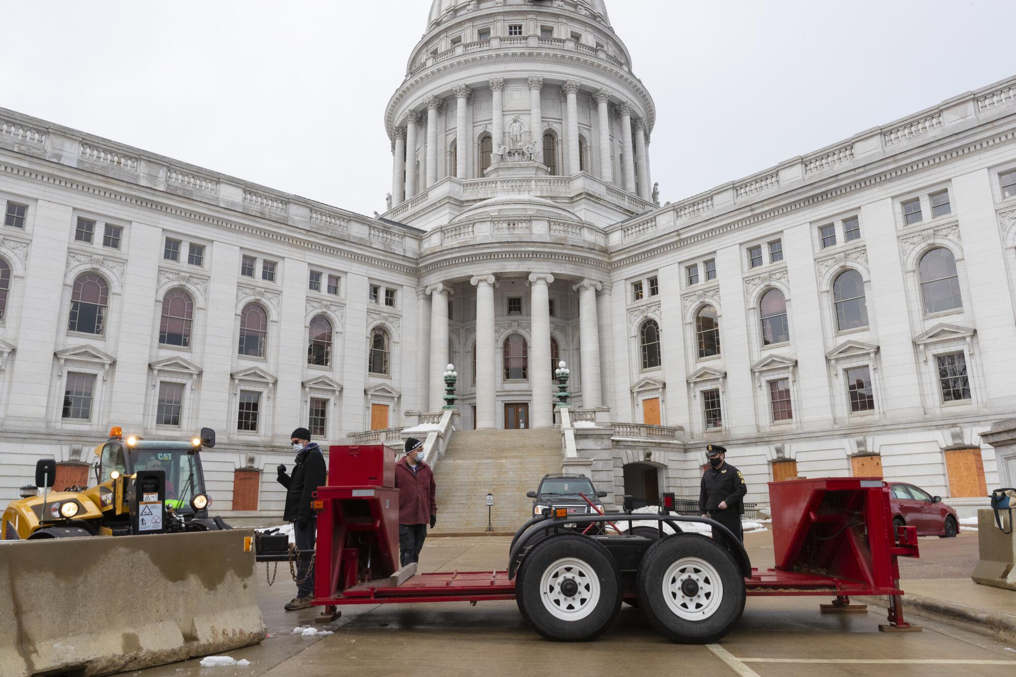 Workers set up a vehicle barricade on one side of the Capitol in Madison, Wis.