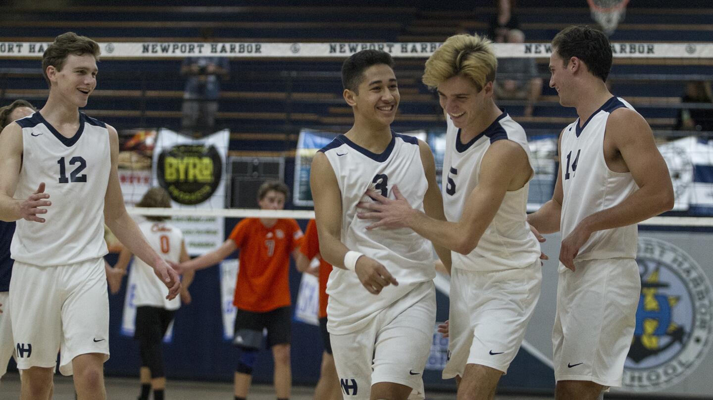 Newport Harbor High's Cole Pender, second from right, is congratulated by teammates, from left, Dayne Chalmers, Joe Karlous and Spencer Lawrence after scoring a point during the second set against Huntington Beach in a Sunset League game on Friday. (Kevin Chang/ Daily Pilot)
