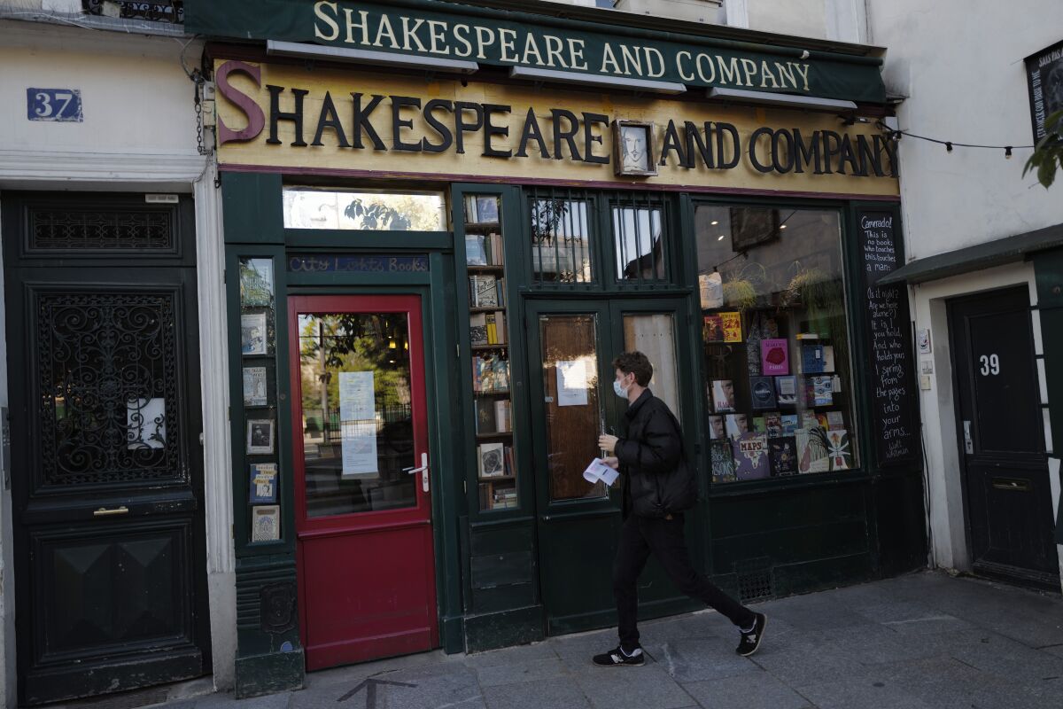 A man walks by the closed English and American literature Shakespeare and Co. bookstore in Paris, France, Thursday, Nov. 05, 2020. Iconic Parisian bookshop Shakespeare and Co. has launched a support appeal to its readers after its owners say that coronavirus-linked losses, and a crippling months-long lockdown, have left the future of the veritable institution in doubt. "We've been minus 80 percent since the first confinement in March, so at this point we've used all our savings," Sylvia Whitman, daughter of the shop's co-founder George Whitman, told the Associated Press. (AP Photo/Francois Mori)