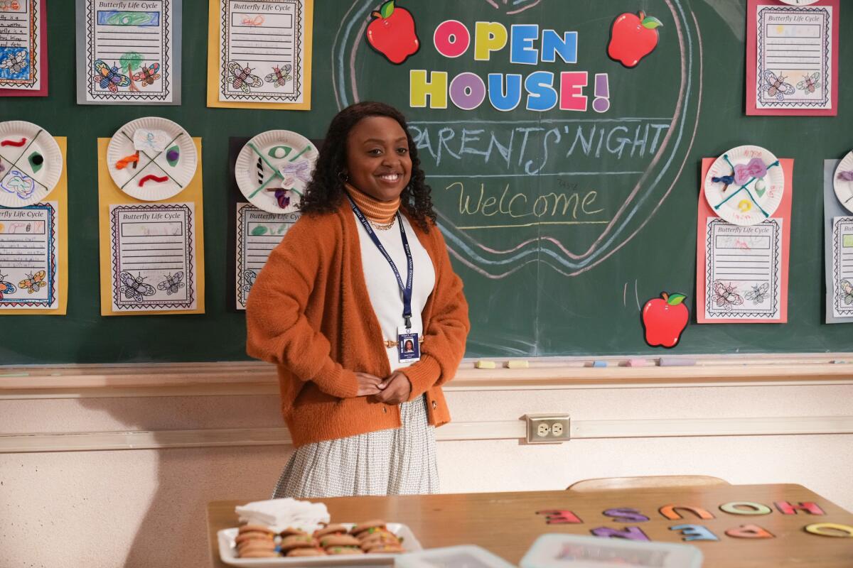 A teacher stands in front of a chalkboard that reads "Open House! Parents' Night. Welcome."
