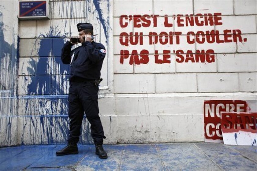 A riot police officer stand by a protest sign "It's ink, not blood that should run" stenciled on the wall of Syrian embassy in Paris by Members of French watchdog organization Reporters Without Borders (RSF), Tuesday May 3, 2011. This action marks World Press Freedom Day. (AP Photo/Thibault Camus)