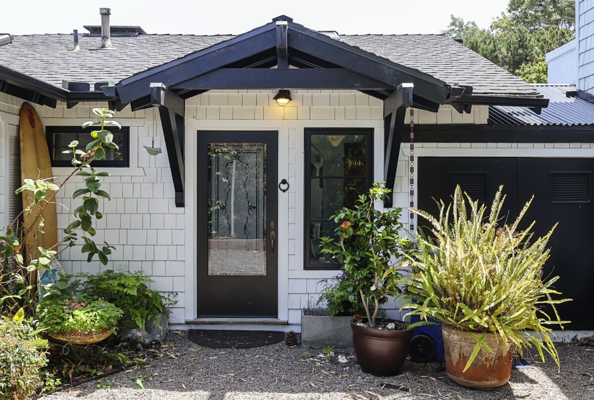 A front entrance view of newly painted white exterior walls and black trim by architect at a beach home.