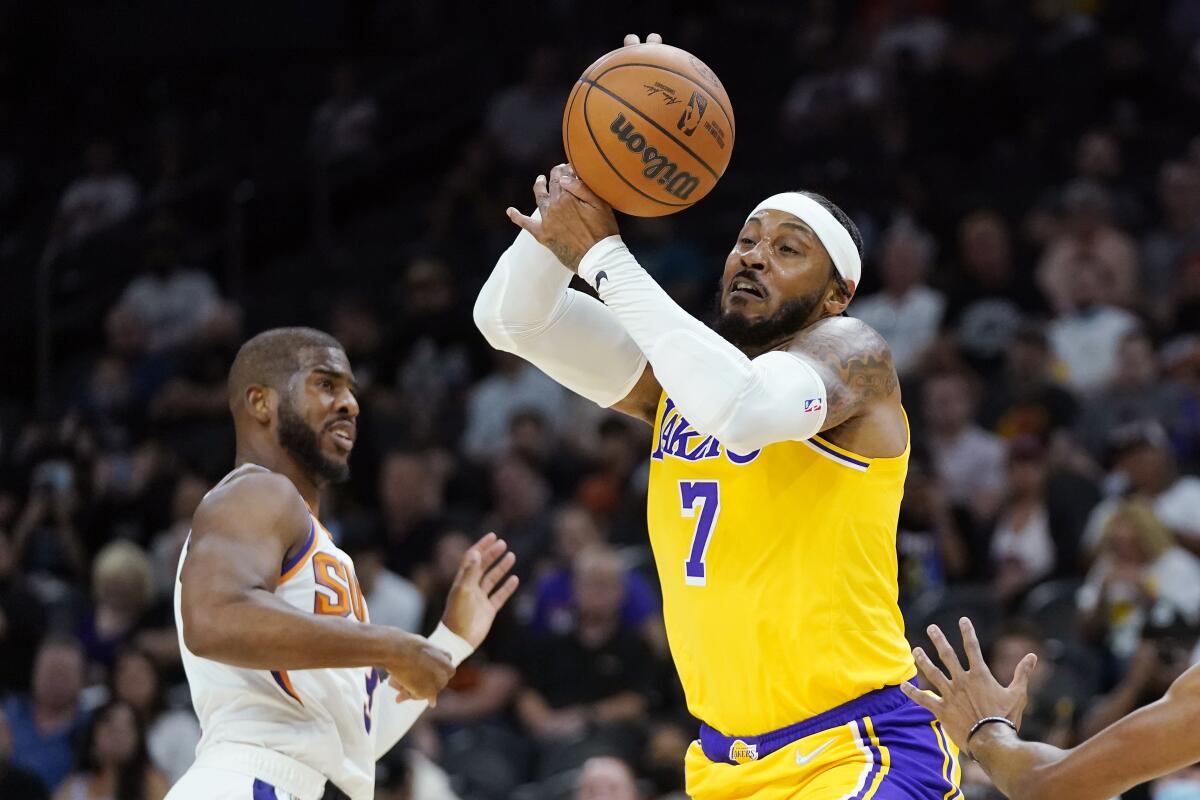 Lakers forward Carmelo Anthony grabs a rebound as Phoenix Suns guard Chris Paul watches.