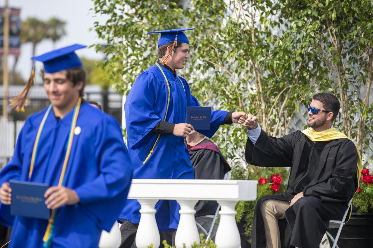 Glenn Atkins gives a fist bump to Dr. Morgan Smith during the 2021 Fountain Valley High School commencement on Wednesday.