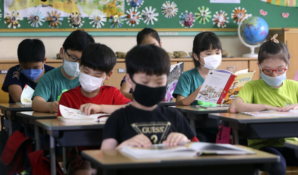 Alumnos surcoreanos de una escuela primaria con máscaras como precaución contra el virus del Síndrome Respiratorio de Oriente Medio, o MERS, durante una clase en su escuela de Busan, Corea del Sur, el 9 de junio de 2015. Corea del Sur está decidida a poner fin esta semana al brote de MERS, y afirmó que los próximos días serán clave para superar la crisis sanitaria. (Cha Geun-ho/Yonhap via AP) NO PUBLICAR EN COREA