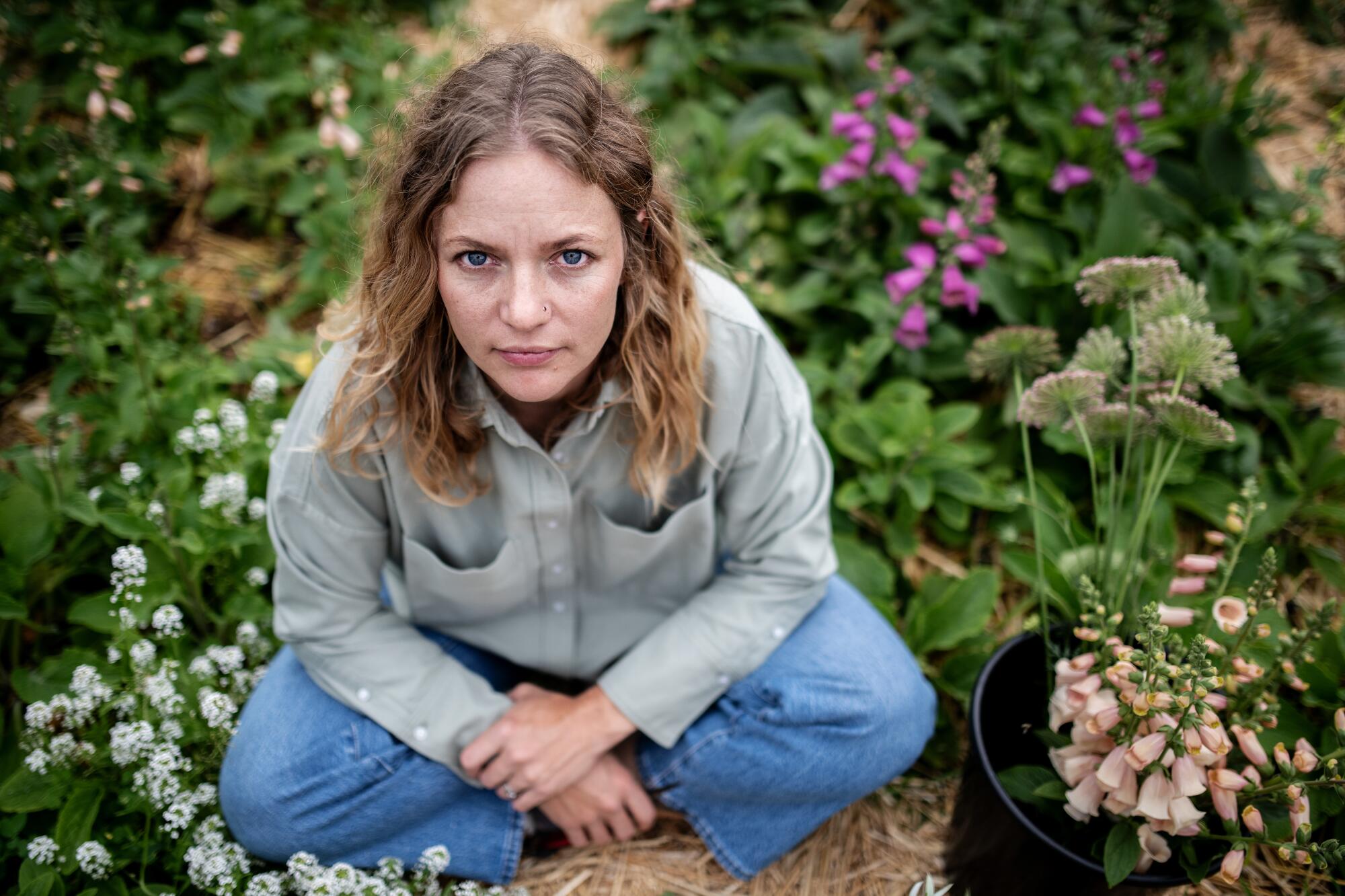 A woman sits amid flowers in her backyard 