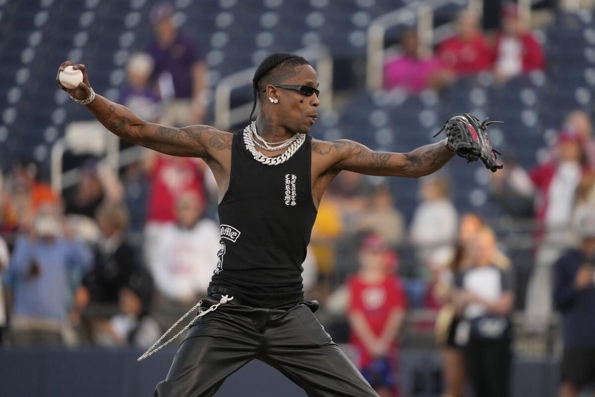 Rapper Travis Scott wears a black sleeveless shirt while throwing out the first pitch at a baseball game