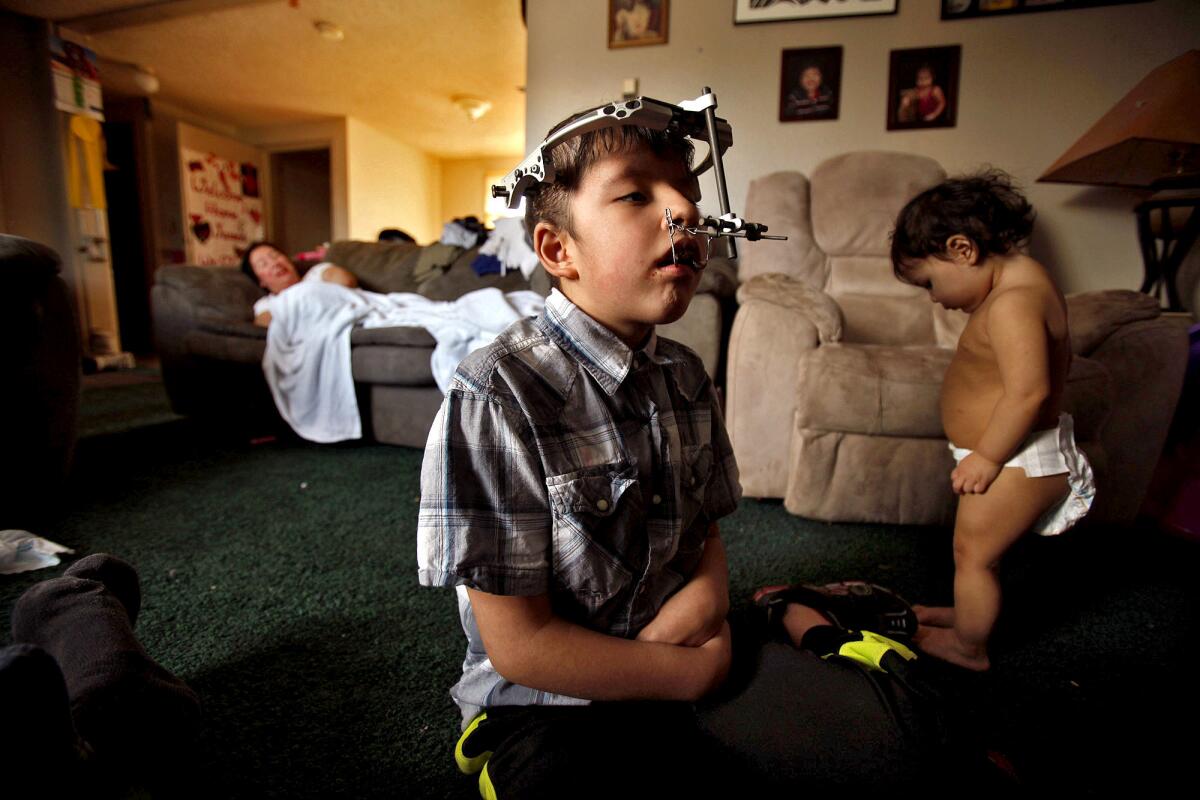James Weatherwax, 11, watches television next to his sister Abby Lane, while their mother, Kecia Weatherwax, rests on a couch in the living room of their home in Klawock, Alaska.