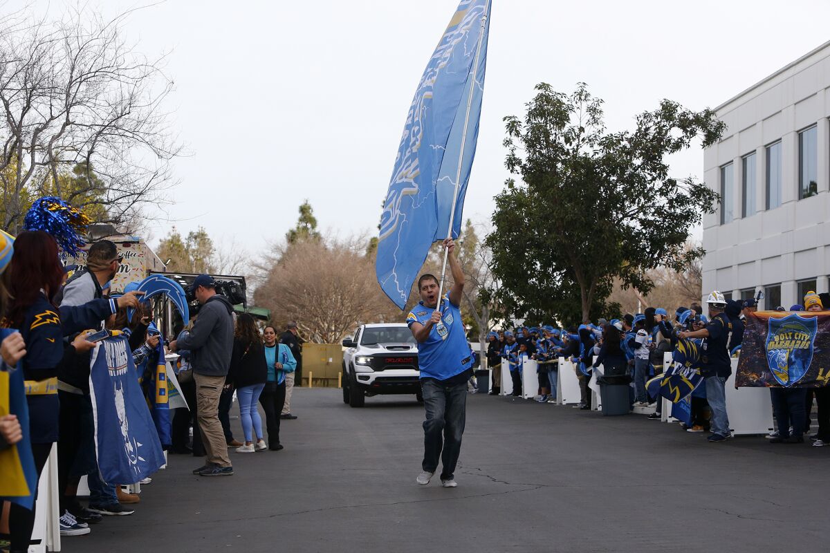 Guillermo Sandoval, 42, of Long Beach runs with his Chargers flag as players arrive in Costa Mesa.