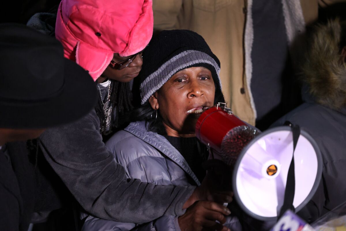 A woman speaks through a megaphone while another person leans over her to hold it.