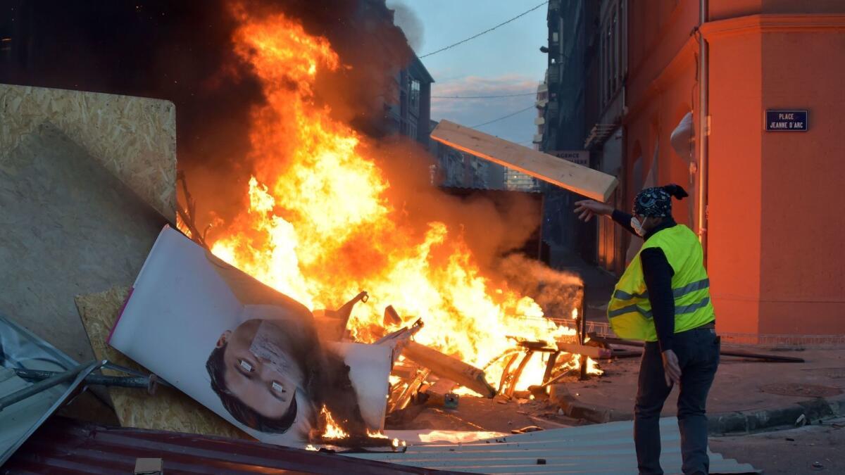 A demonstrator throws a piece of wood on a burning barricade during a "yellow vest" protest against rising oil prices and living costs in Toulouse, southern France, on Saturday.