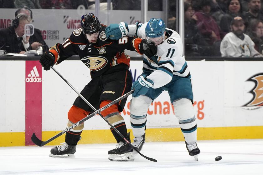 Anaheim Ducks defenseman Olen Zellweger, left, and San Jose Sharks center Luke Kunin battle for the puck during the second period of an NHL hockey game Wednesday, Jan. 31, 2024, in Anaheim, Calif. (AP Photo/Mark J. Terrill)