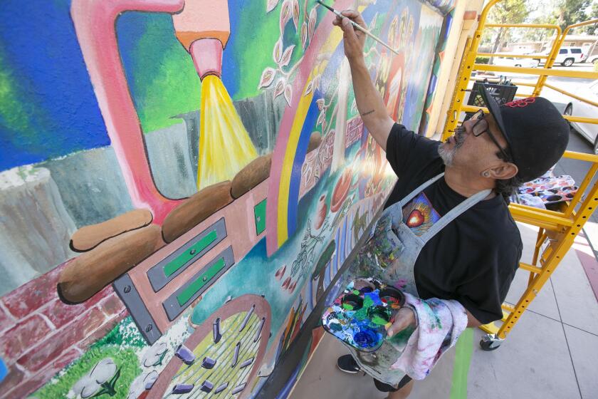 Muralist Mario Chacon worked on restoring a mural painted by fellow muralist Michael Schnoor in 1980 at the San Ysidro health clinicon Tuesday, October 29, 2019. Schnoor passed away in 2016. Schnoor passed away recently.