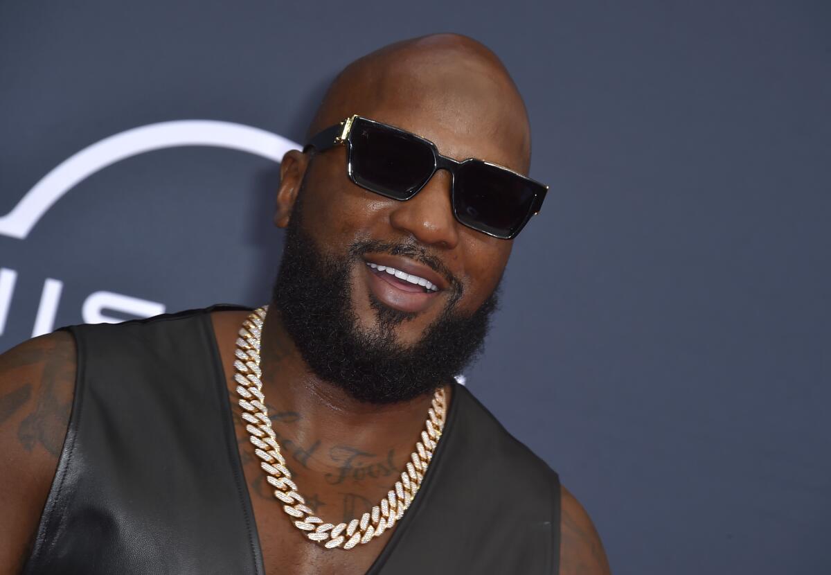 Jeezy poses at an awards show in dark glasses, a black leather vest and a heavy gold chain 