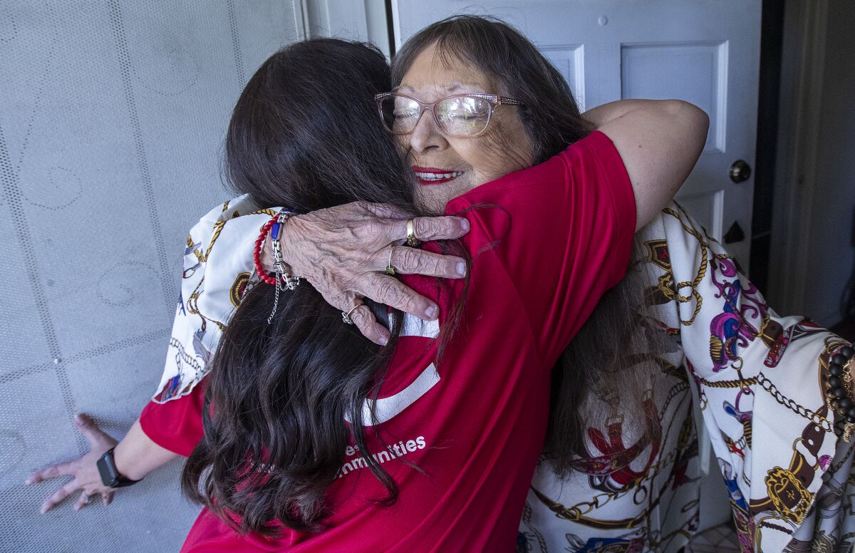 Karen Kochara receives a hug from Maxine Shelley after delivering a meal to her at her home in Valley Village. 