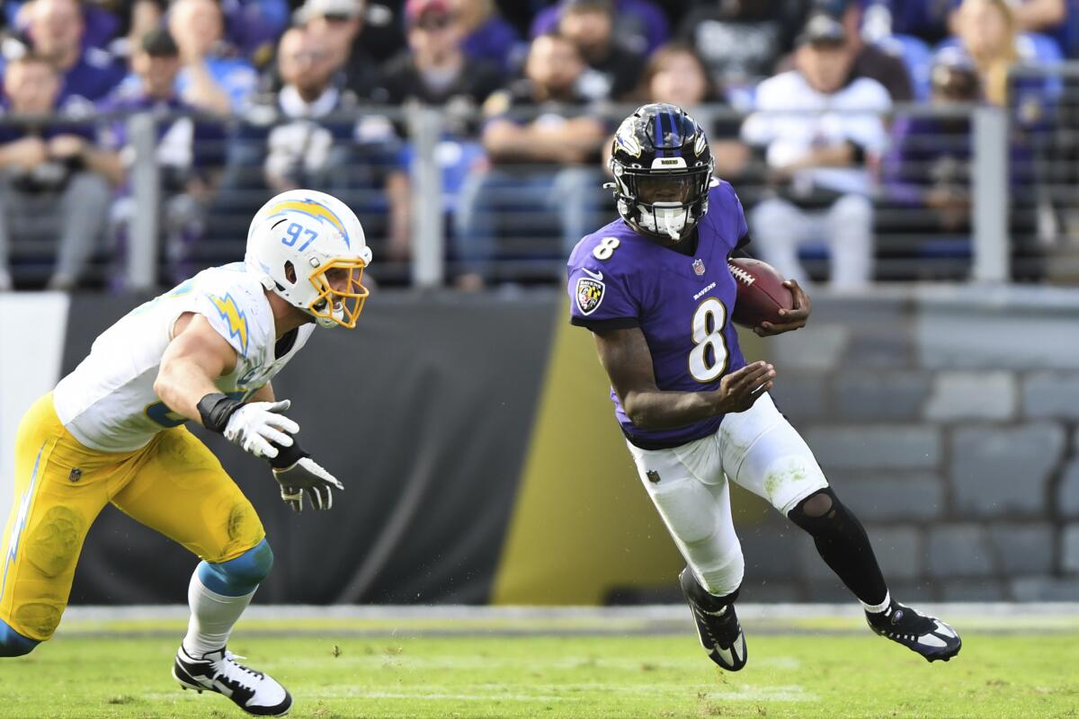 Ravens quarterback Lamar Jackson, right, carries the ball past Chargers defensive end Joey Bosa.