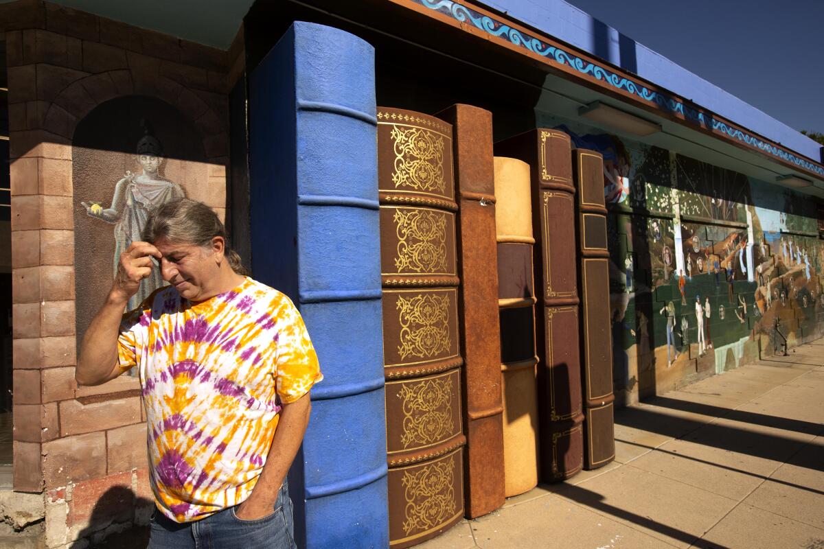 A man in a tie-dye shirt walks in front of a bookstore decorated to look like a row of oversized books.