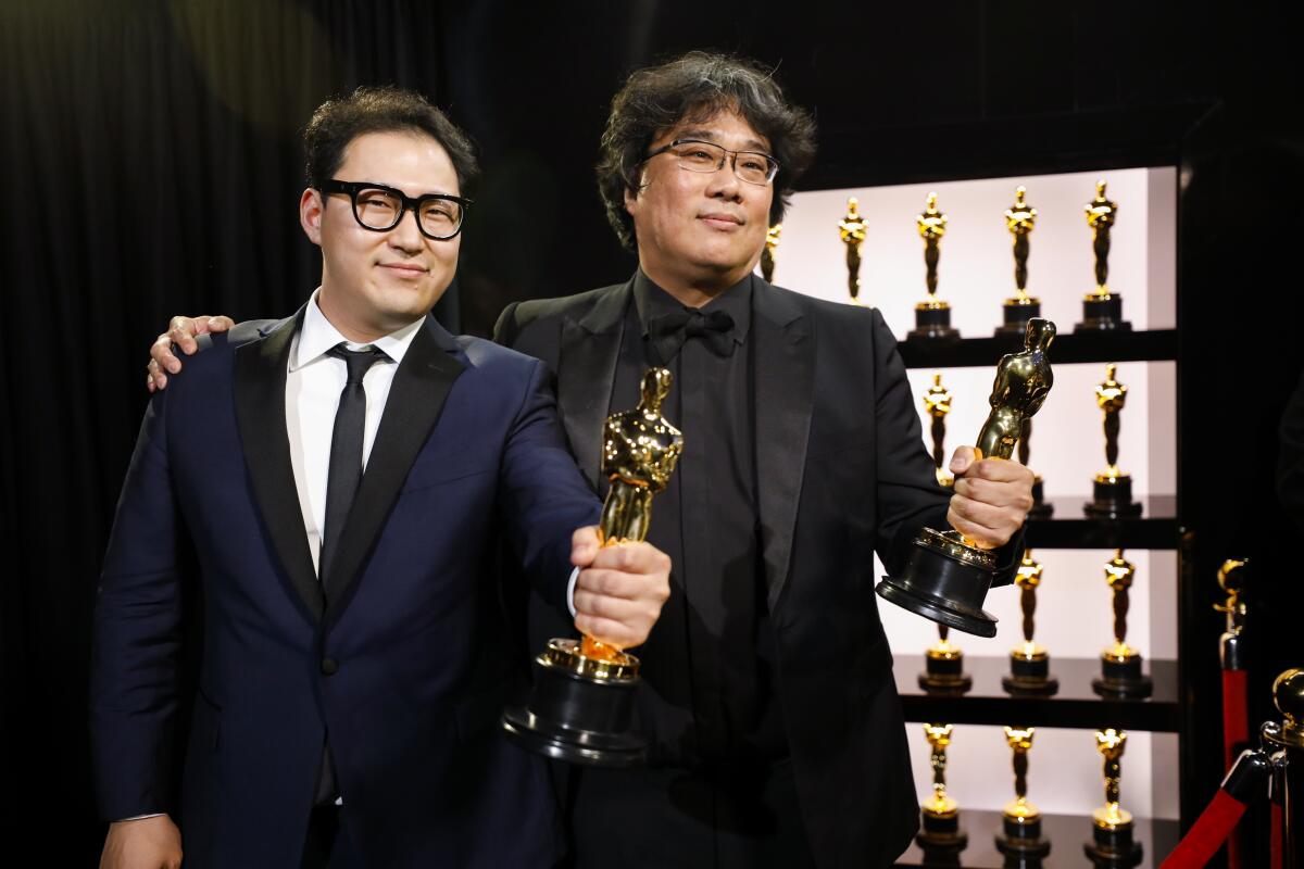 Han Jin Won, left, and Bong Joon Ho, winners of the original screenplay Oscar for “Parasite,” backstage