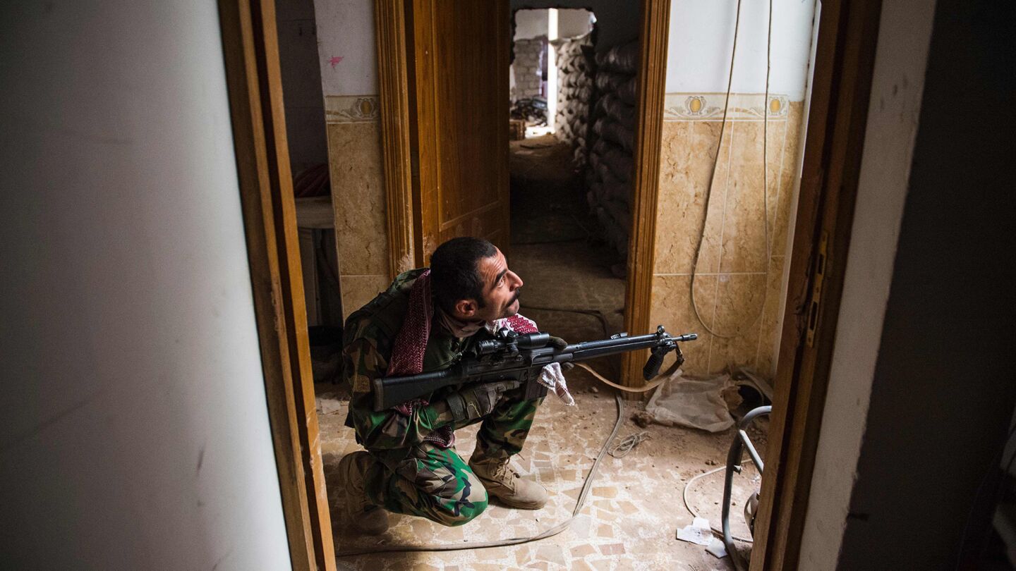 A peshmerga fighter looks for militants as he and his team move between buildings in Bashiqa.