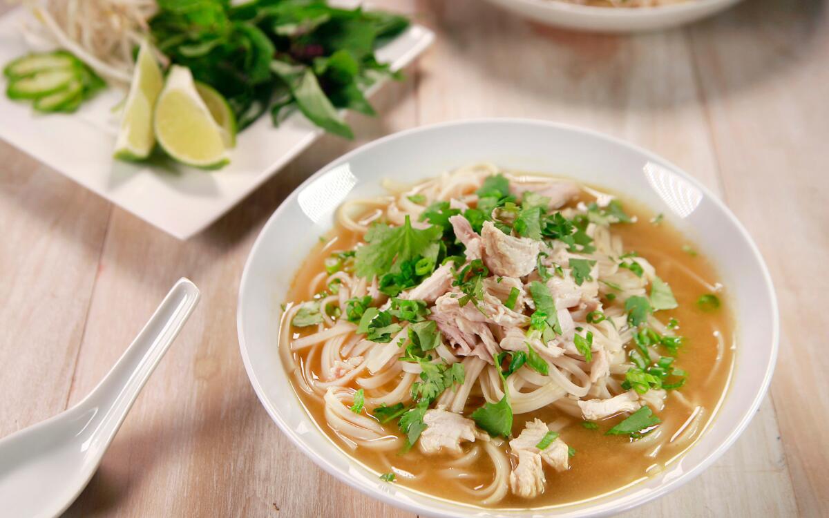 A bowl of Ph Ga Nhanh (Quick Chicken Pho ) with rice noodles, chicken and fresh cilantro peeking out from the broth.